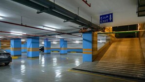 Un garaje para estacionamiento con pilares azules, un coche y un letrero de salida.