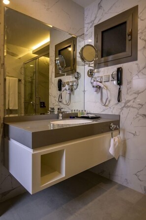 Un bany modern amb un mirall gran, un telèfon integrat i un lavabo amb rentaperros.