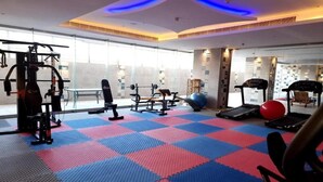 Un gimnasio con diversos equipos de ejercicio, una pelota roja para hacer ejercicio y una cinta de correr.