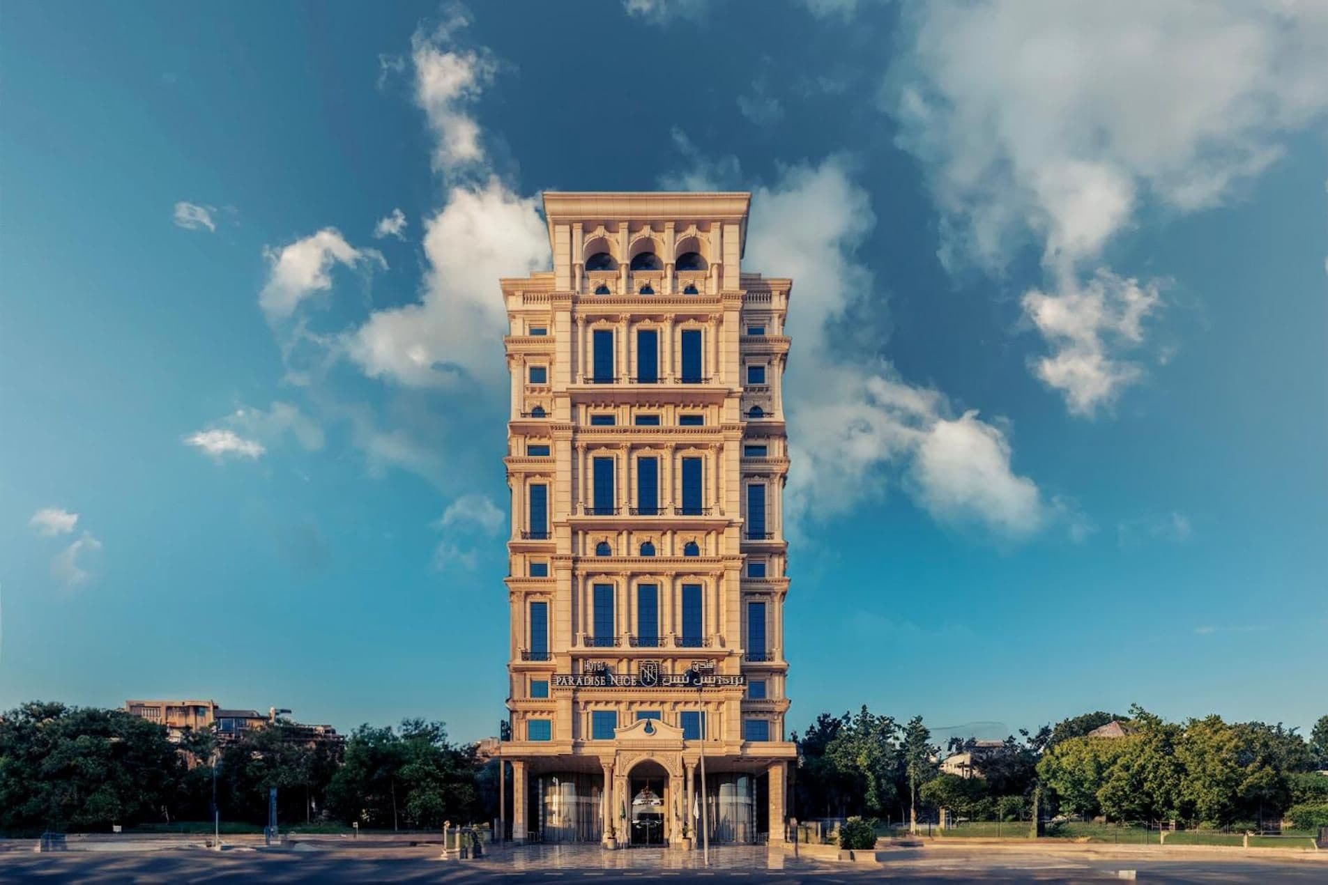 A multi-story hotel with a classical architectural style, featuring a central entrance with a grand archway and a sign above it.