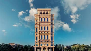 A multi-story hotel with a classical architectural style, featuring a central entrance with a grand archway and a sign above it.