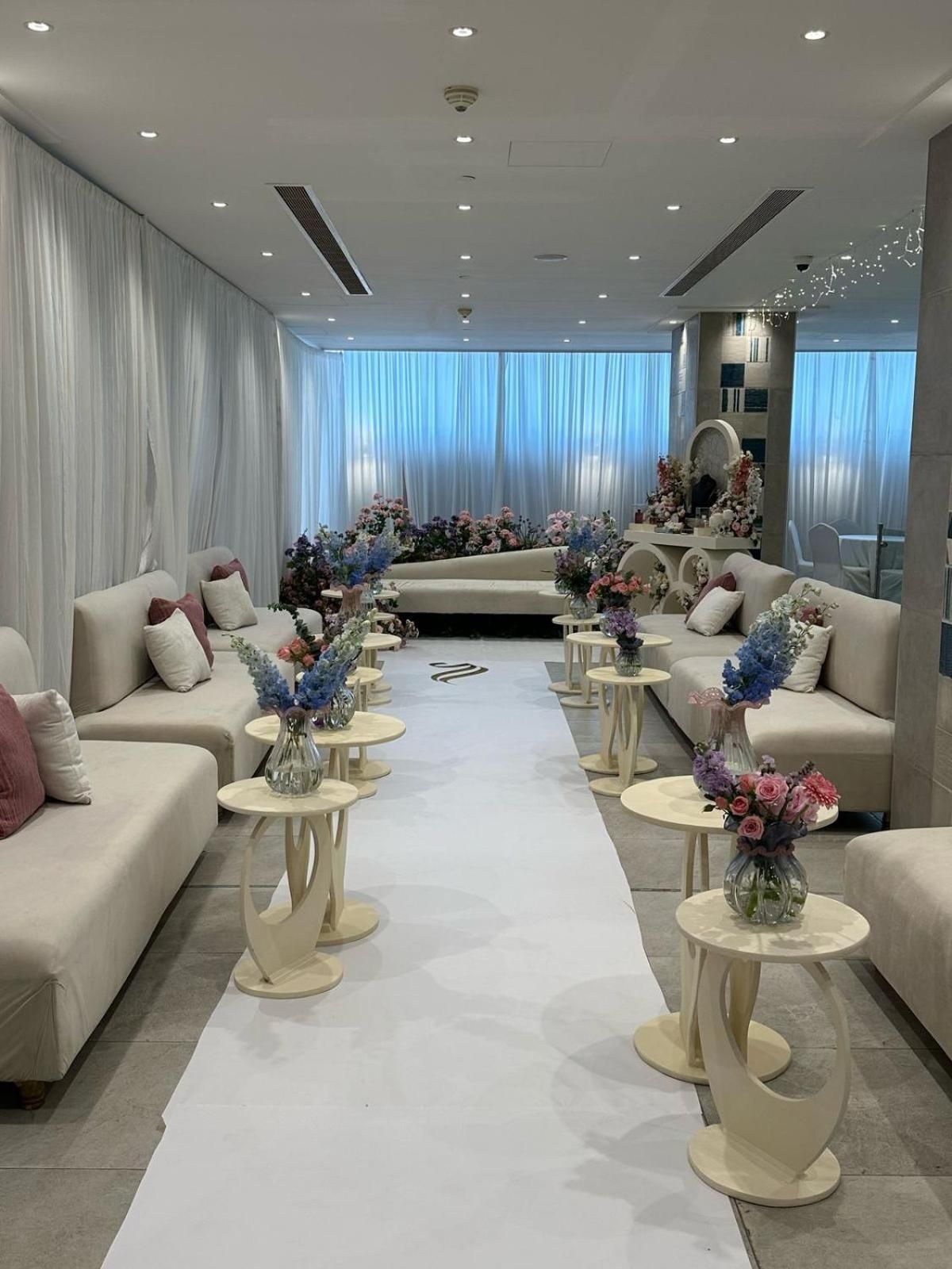 Un moderno vestíbulo de hotel con sofás, mesas redondas y arreglos florales.