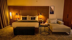 Una habitación de hotel con una cama grande, un sofá, una mesita y una mesita de noche.