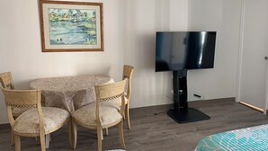 Quarto de hotel com mesa de jantar, duas cadeiras, televisão e cama.