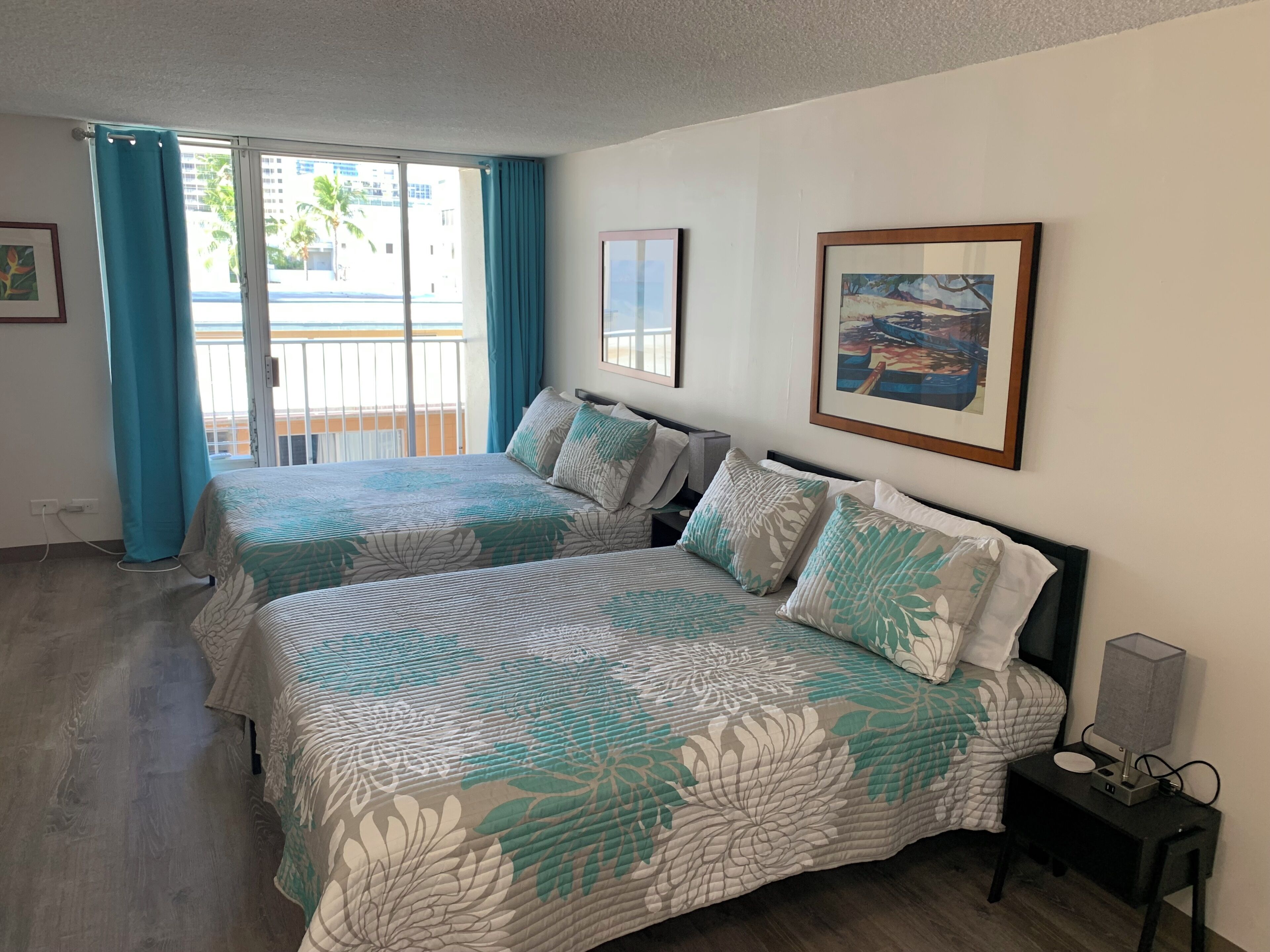 A hotel room with two beds, a balcony, and a painting on the wall.