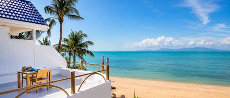 A beachfront property with a balcony, a table with chairs, and a view of the ocean.