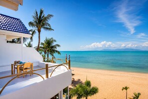 A beachfront property with a balcony, a table with chairs, and a view of the ocean. - B1 Beachfront (Koh Samui)