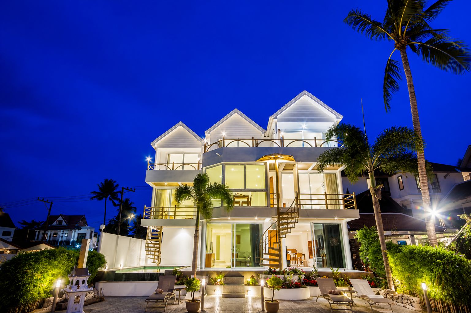 A multi-story house with a balcony, a staircase, and a pool area.