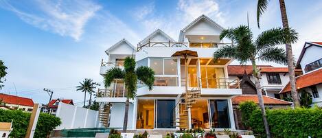 A multi-story residential building with a swimming pool, outdoor seating, and lush landscaping.