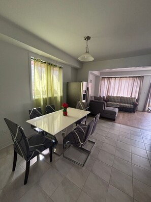 Ein Essbereich mit Tisch, Stühlen, einer Couch und einem Fernseher.