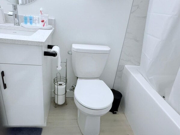A bathroom with a toilet, a sink with toiletries, and a bathtub. - Cozy 2BR Basement Suite Rosenthal Stay by WEM (Edmonton)