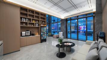Un vestíbul modern amb una recepció, zona de seients i una finestra gran que ofereix vistes a l'exterior.