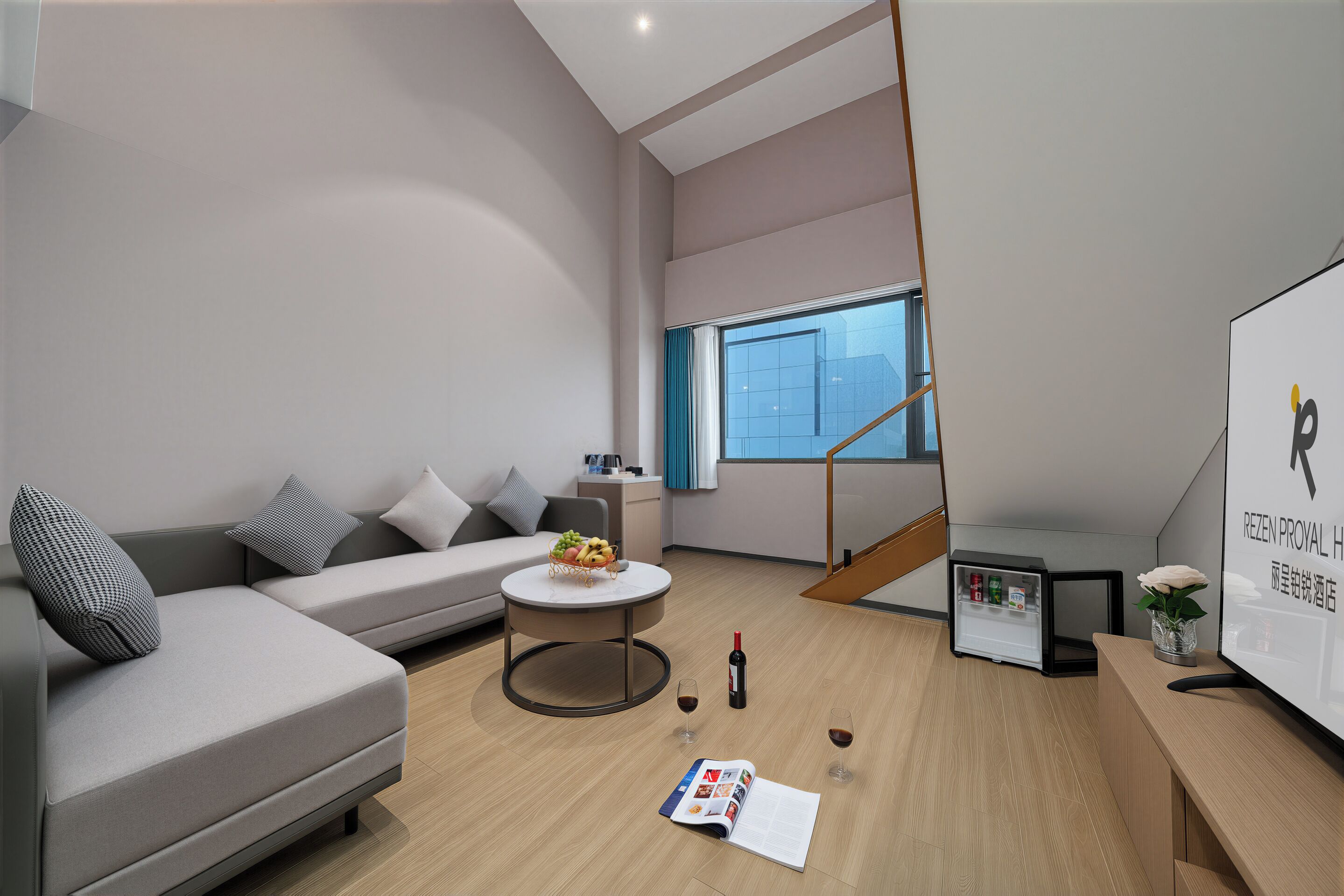 A modern living room with a sofa, a coffee table, a small dining table, and a refrigerator.