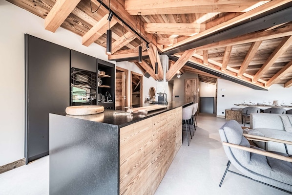 Eine moderne Küche mit Holzboden, einer schwarzen Arbeitsplatte und einer Bar mit Hockern.
