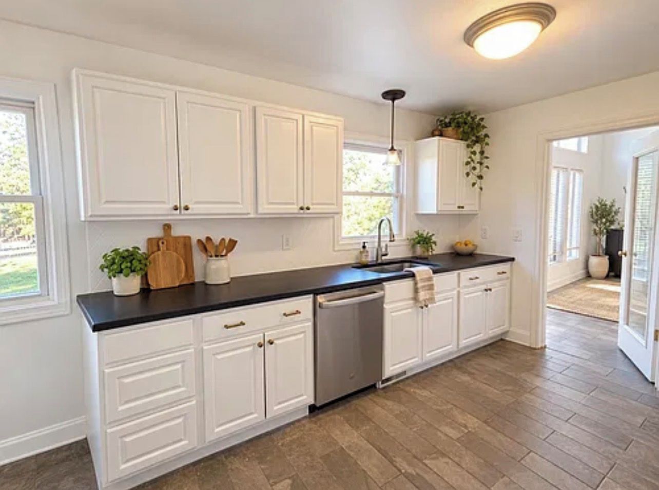 A kitchen with white cabinets, a black countertop, and a dishwasher.