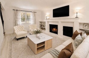 Una sala de estar con chimenea, televisor y sofá.