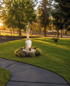 Un parque con una fuente central rodeada de césped y árboles.