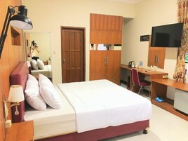 Una habitación de hotel con cama, escritorio, televisión y armario.