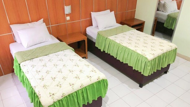 A hotel room with two single beds, each with a green bedspread and white pillows. - Hotel Galuh and Water Park Prambanan  (Prambanan)