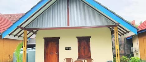 Un bâtiment à deux étages, doté d’un toit à deux versants, d’un porche avec des chaises et d’une enseigne indiquant le nom de l’établissement.