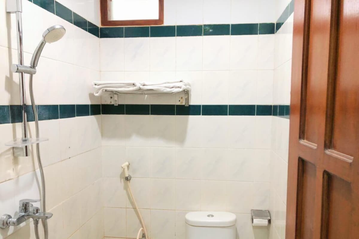 A small bathroom with a toilet, a shower, and a towel rack.