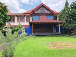 Una casa tradicional con techo rojo, un porche cubierto y un jardín bien cuidado.