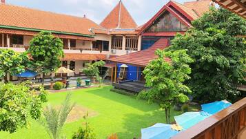 A courtyard with a central lawn, surrounded by buildings with red-tiled roofs and a blue building with a red roof.
