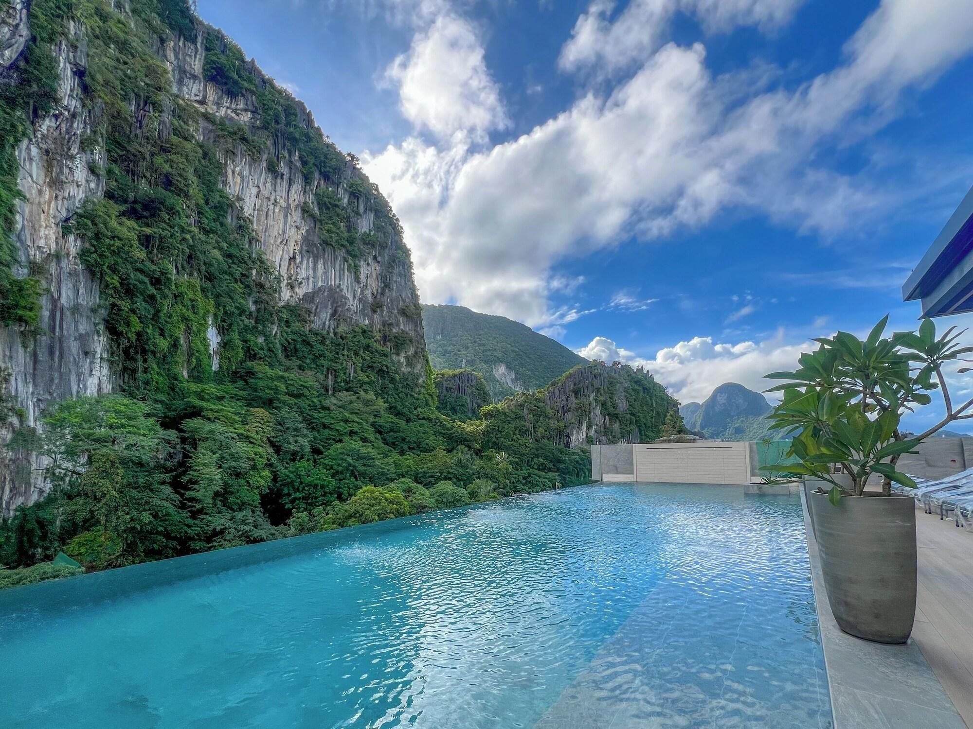 A pool with clear blue water, surrounded by lush greenery and steep cliffs.