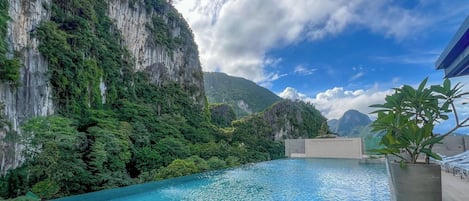 A pool with clear blue water, surrounded by lush greenery and steep cliffs.