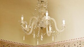 A chandelier with a star-shaped top and multiple arms, hanging from a ceiling with a decorative border. - Roccamelia Experience (Mazara del Vallo)