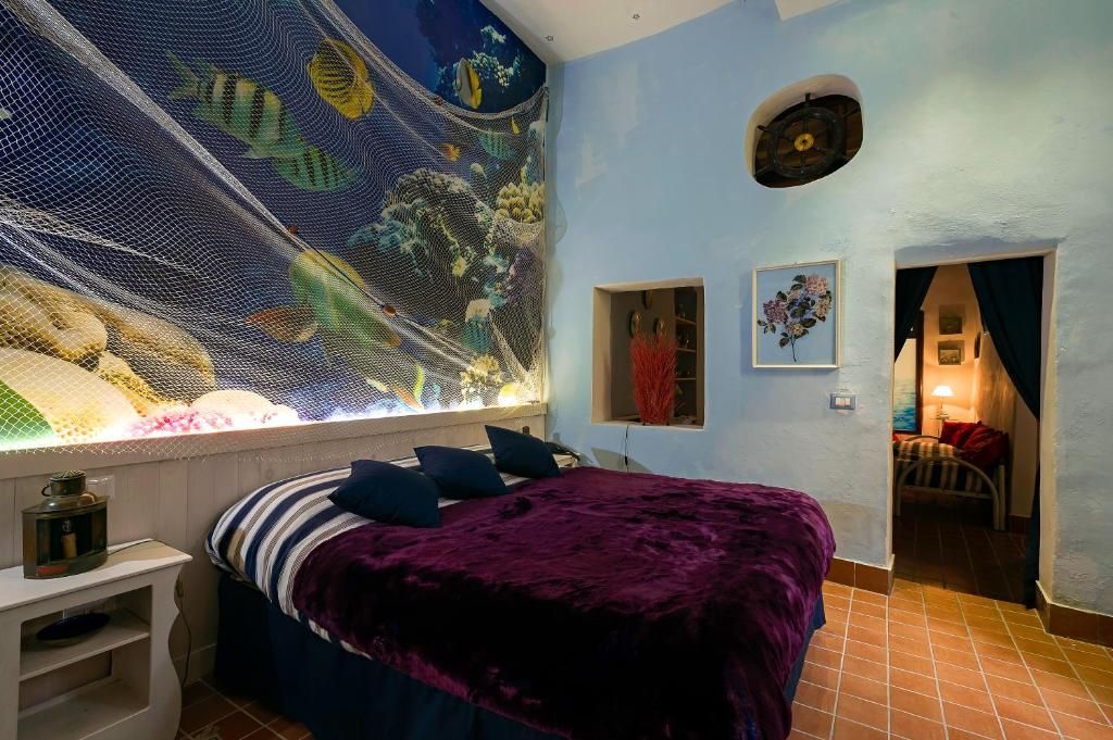 Una camera da letto con un letto, un affresco, una piccola finestra e una porta che dà su un'altra stanza.