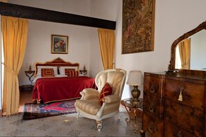 A bedroom with a bed, a chair, a dresser, and a painting on the wall.