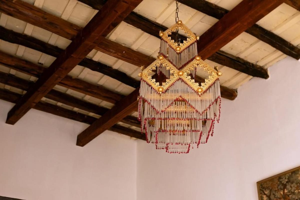 A chandelier with a geometric design hanging from a wooden ceiling.