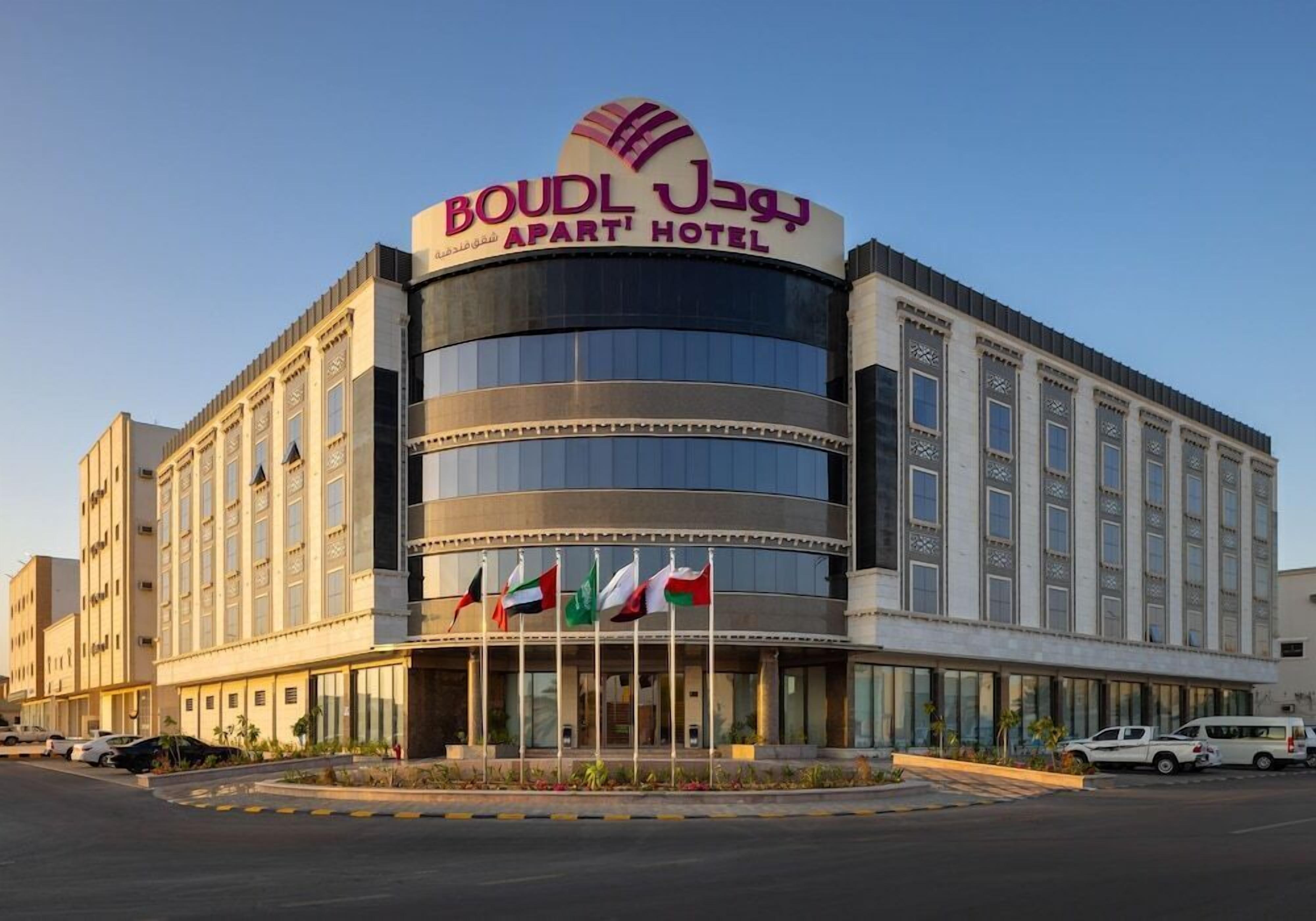 Un hotel con un letrero llamativo, varias banderas y una fachada moderna.