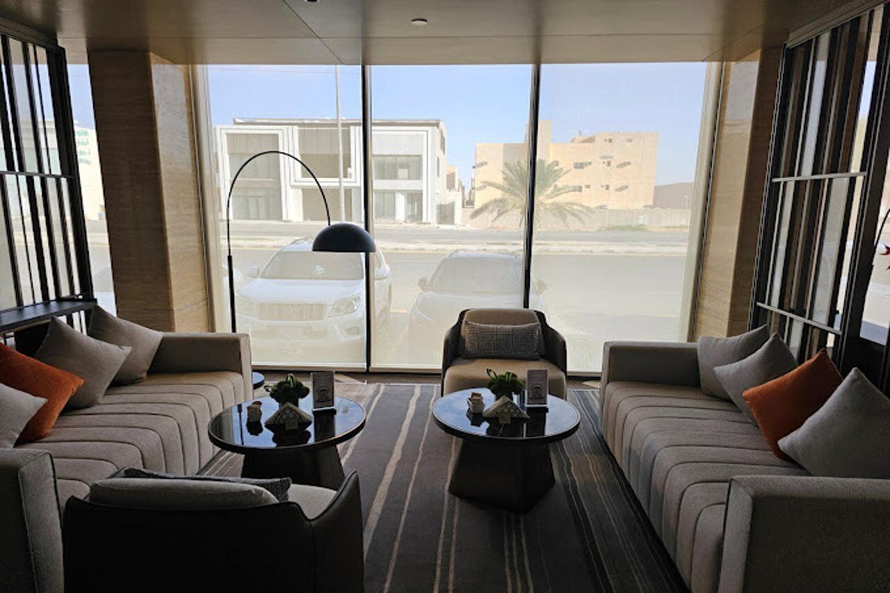 A modern hotel room with a large window, a sofa, a chair, and a coffee table.