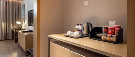 Una habitación de hotel con kitchenette, una cama y un ventanal con cortinas.