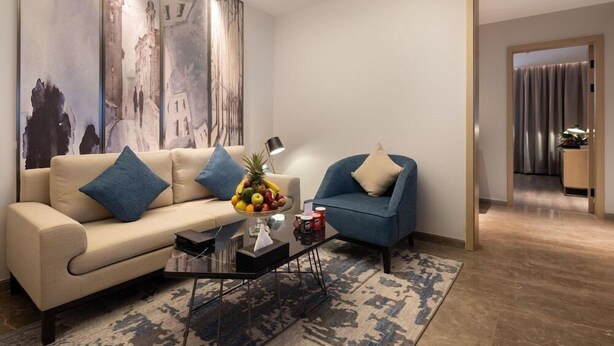 Una sala de estar moderna con un sofá, un sillón, una mesa de centro y un frutero.