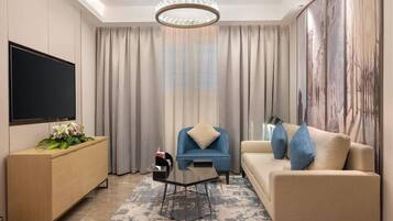 A modern living room with a flat-screen TV, a blue armchair, a beige sofa, and a coffee table.