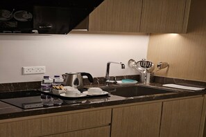 A modern kitchen with a black countertop, stainless steel appliances, and wooden cabinets. - Boudl Al Rawdha (Buraydah)