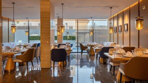 Un restaurante moderno con piso pulido, mobiliario contemporáneo e iluminación colgante.