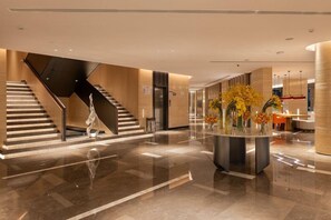 A modern lobby with a central staircase, a reception desk, and a decorative vase with flowers. - Boudl Al Rawdha (Buraydah)