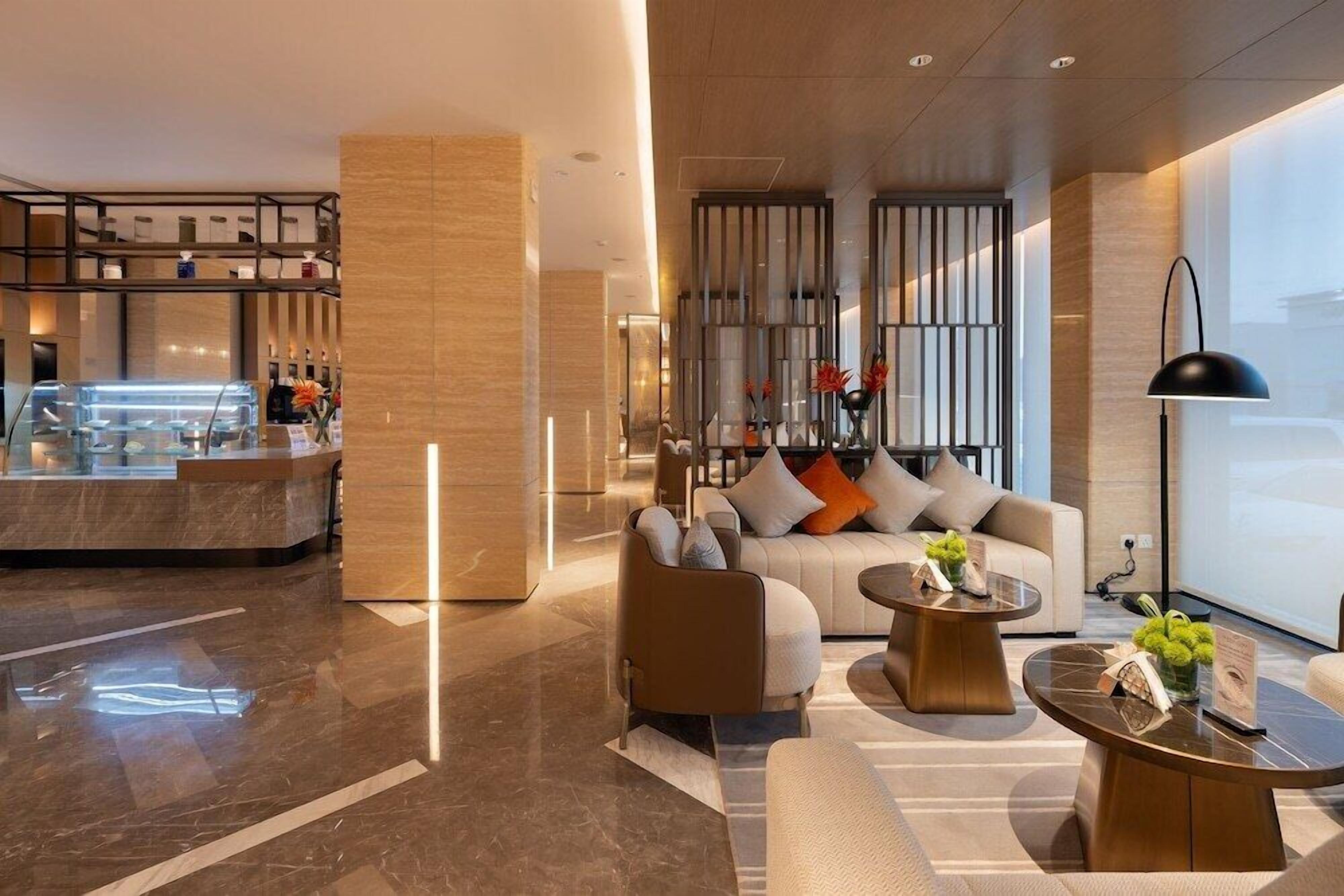 A modern hotel lobby with a seating area, a bar, and a large window.