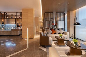 Un moderno vestíbulo de hotel con un área de descanso, un bar y un amplio ventanal.