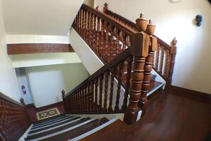 A wooden staircase with a handrail and a patterned carpet. - Nscc Hotel Vigan by Zuzu (Vigan)