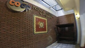 Ein Hotel Eingang mit einer Ziegelwand, einem Schild für 'coop NSEC HOTEL VEGAN' und einem dekorativen Wappen.