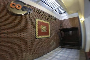 A hotel entrance with a brick wall, a sign for 'coop NSEC HOTEL VEGAN', and a decorative emblem. - Nscc Hotel Vigan by Zuzu (Vigan)