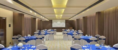 A conference room with rows of tables, chairs, and a projection screen.