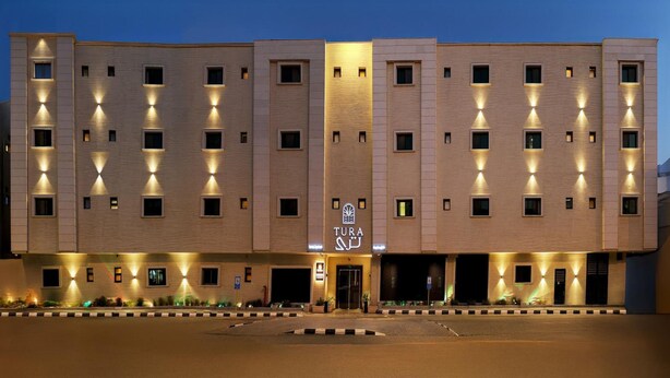 A multi-story hotel with a symmetrical facade, evenly spaced windows, and a central entrance with a logo. - Tura Residence Sulemania (Riyadh)
