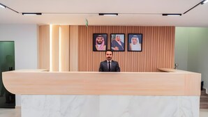 A reception desk with a marble top and a wooden backdrop with framed portraits. - Tura Residence Sulemania (Riyadh)