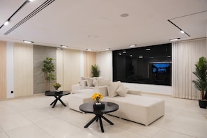 A modern living room with a sectional sofa, a round coffee table, and a flat-screen TV. - Tura Residence Sulemania (Riyadh)